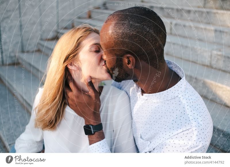 Happy diverse couple kissing on street bonding romantic positive relationship love happy affection embrace modern casual urban city lifestyle multiethnic