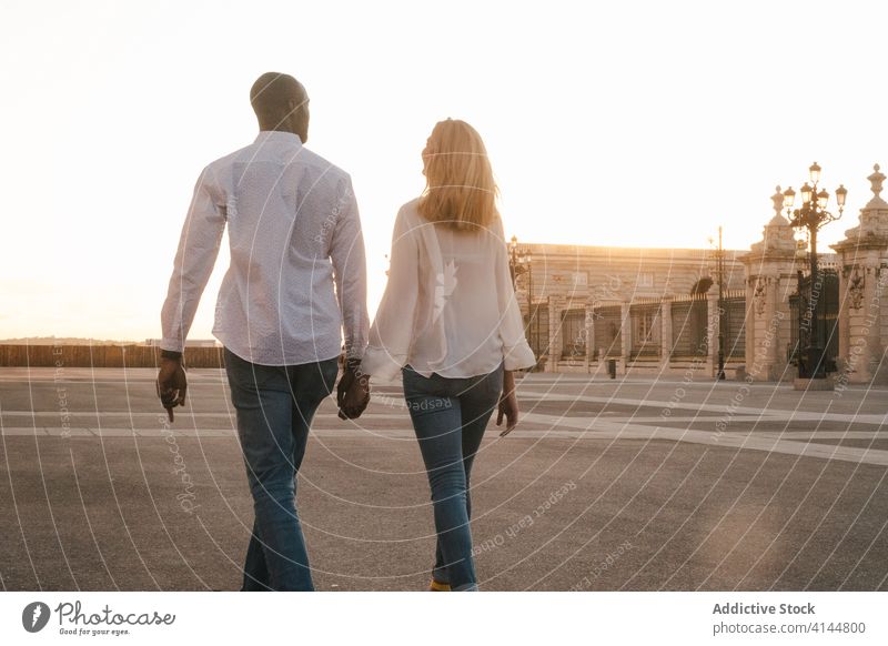 Romantic multiethnic couple holding hands and strolling along city street walk romantic carefree relationship fondness harmony affection casual spain madrid