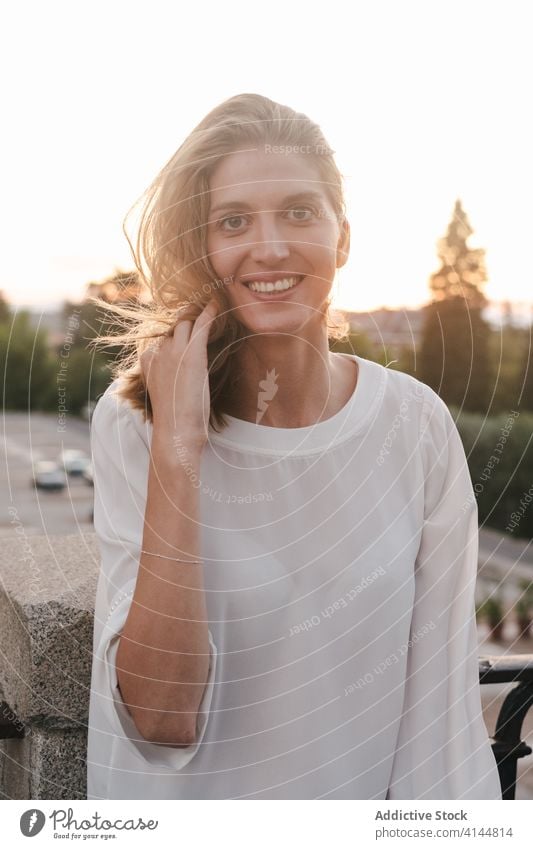 Joyful woman supported on sidewalk railing and laughing joyful rest expressive cheerful toothy smile urban enjoy sunset delight relax happy madrid spain street