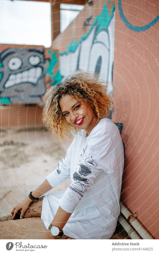 Provocative female millennial on street provocative woman graffiti city urban trendy unemotional creative hairstyle ethnic black african american stone