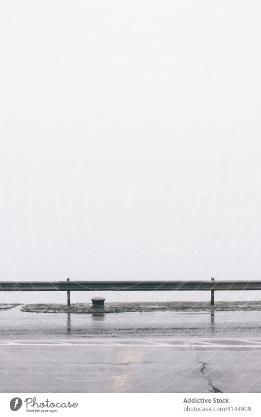 Wet asphalt road in foggy city wet morning empty mist roadway gloomy metal fence old weathered haze amazing tranquil magnificent cement scenery peaceful calm