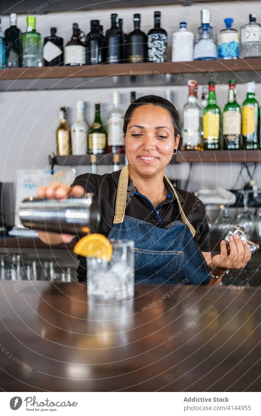 Cheerful ethnic bartender in cafe woman counter barkeeper positive alcohol drink barmaid female service beverage professional happy smile employee apron work