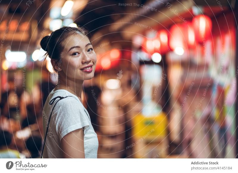 Cheerful ethnic woman in night city happy smile street young positive cheerful urban glad joy asian female casual lifestyle illuminate evening modern optimist