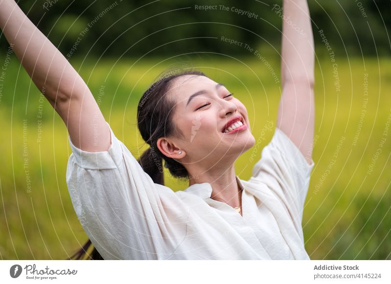 Carefree woman in green field carefree enjoy freedom summer nature rice smile tranquil female asian ethnic happy rest optimist positive glad stand relax lady