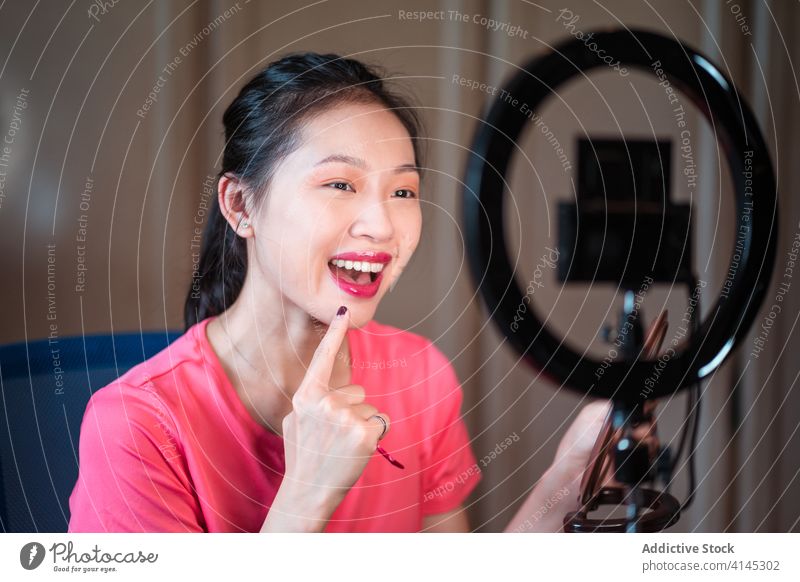 Beauty blogger applying makeup during shooting session beauty vlog woman cosmetic foundation record video young asian female ethnic camera light lamp mirror