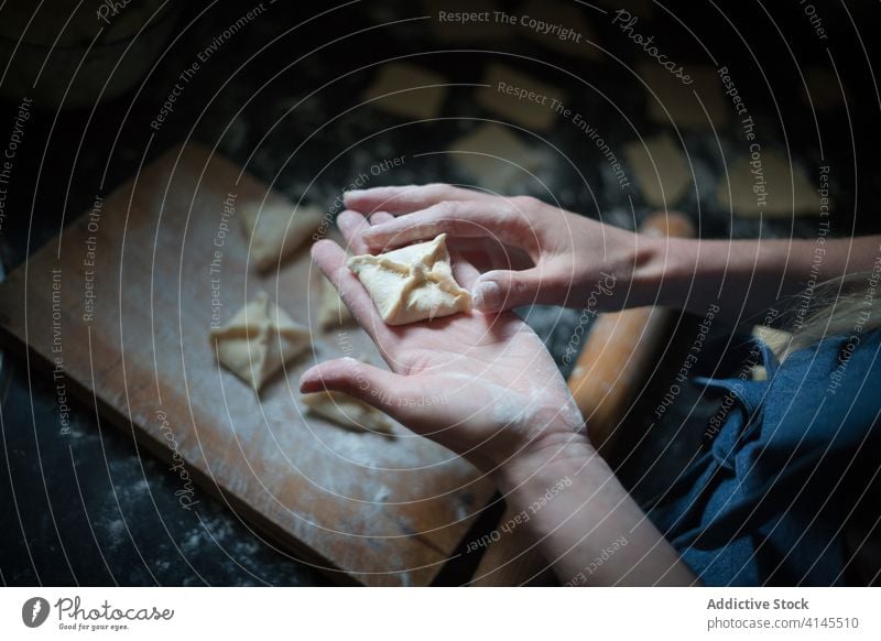 Faceless cook preparing dumplings in kitchen prepare food culinary recipe domestic cuisine lunch menu raw dough square shape decoration woman soft fresh