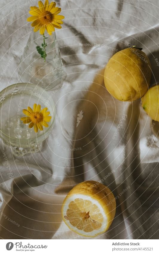 Glass of cocktail arranged with vase of yellow chamomile and fresh lemons glass composition delicate natural organic healthy vitamin drink plant flower decor