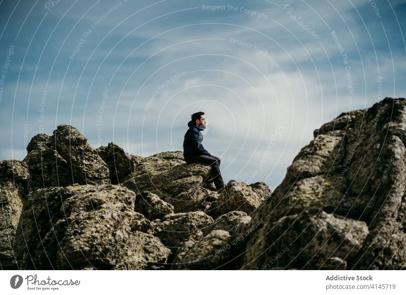 Man traveler admiring mountains man ridge admire stone sit eyes closed cloudy sky puerto de la morcuera spain male edge nature trip landscape tourism wanderlust