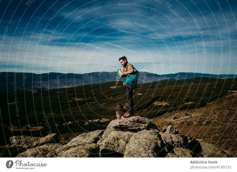 Male hiker with dog in mountains man rest trip sky overcast bottle puerto de la morcuera spain male water stone labradoodle cute journey nature stand rock