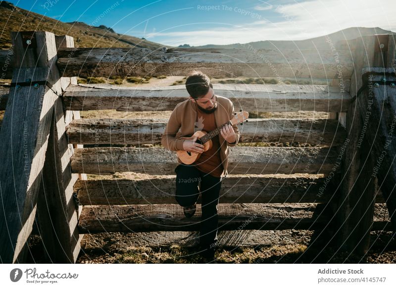 Male traveler resting near fence man mountain lean sunny daytime puerto de la morcuera spain male countryside wooden ukulele barrier relax nature journey trip