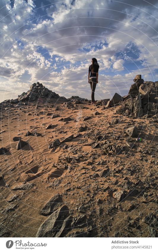 Unrecognizable tourist exploring picturesque desert with shapeless stones in daylight explore nature tourism spectacular idyllic sand bumpy scenery Asia woman