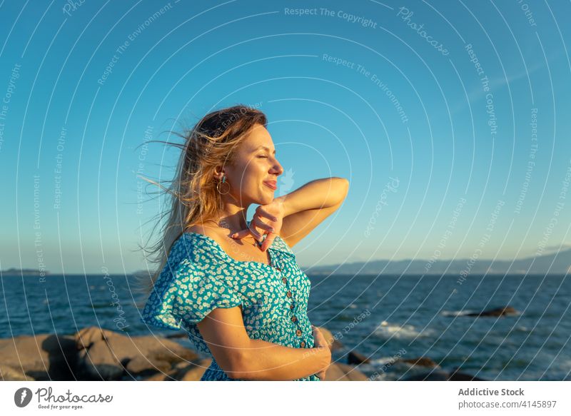 Smiling young female tourist recreating against calm ocean during sunset woman recreation seashore eyes closed enjoy happy smile traveler summer vacation