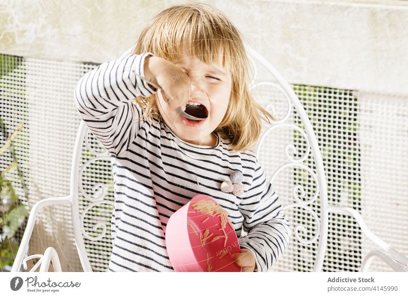 Charming girl sitting at table during breakfast adorable child morning terrace smile food bowl kid happy relax sunny summer courtyard backyard little healthy