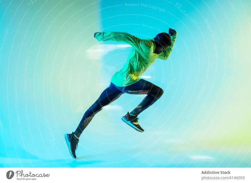 Sportsman starting sprint in studio sportsman runner athlete sportswear determine tracksuit active sprinter jogger physical neon young black african american