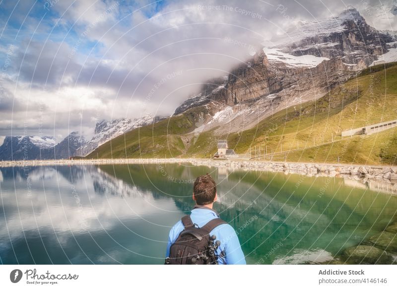 Unrecognizable traveler contemplating breathtaking lake in mountains under cloudy sky tourist ridge contemplate nature highland magnificent reflection