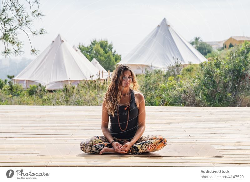 Calm woman relaxing in Ardha Padmasana yoga posture practice half lotus ardha padmasana camp harmony peaceful calm healthy tranquil tropical park resort female