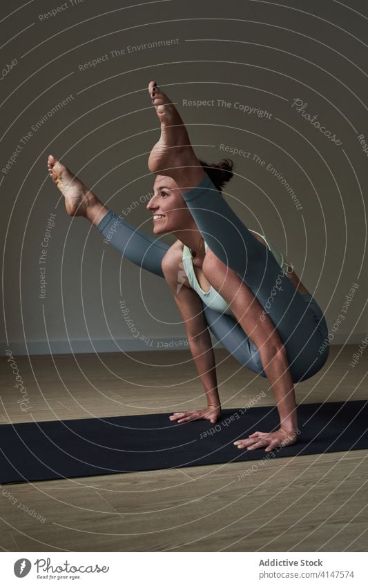 Cheerful sportswoman improving concentration while doing Tittibhasana yoga pose practice ashtanga vinyasa firefly happy strong athlete smile balance exercise