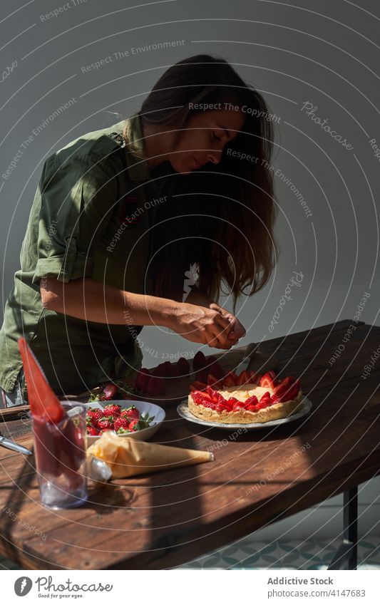 Woman decorating cake with strawberries pie woman strawberry cook decorate confectionery homemade female delicious table food yummy palatable sweet treat