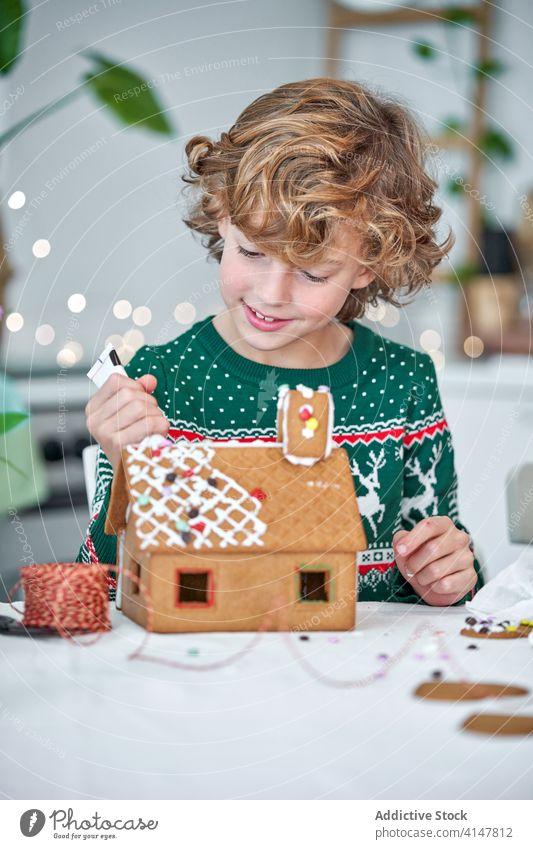 Little boy decorating gingerbread houses kid christmas icing prepare make decorate home kitchen little child winter festive holiday homemade occasion male