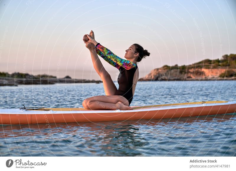 Flexible woman doing yoga on paddleboard sunset pose surfer balance sea female water healthy nature harmony relax tranquil serene sky calm ocean peaceful lady