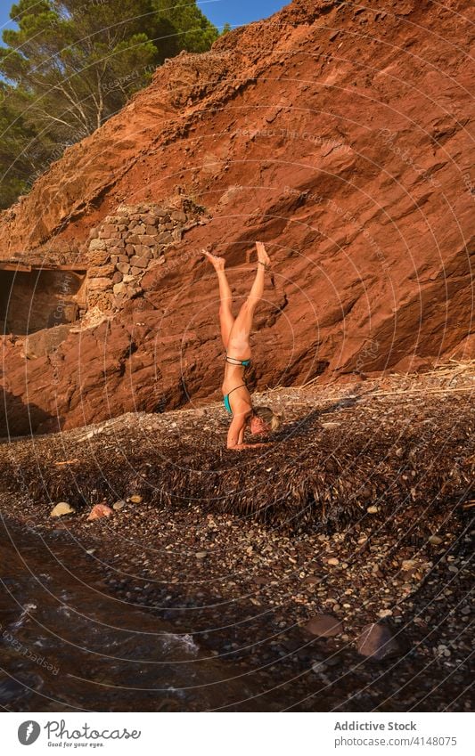 Woman doing the Handstands yoga position on a beach vertical wave sea motion natural forest pose inverse handstand fitness sport strength health woman athlete