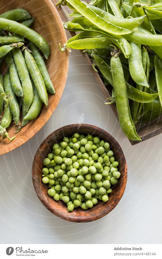 Bowl with heap of pea pods and green peas bowl fresh crunchy abundance vegetarian raw healthy bean nutrient wooden crispy product pile uncooked vitamin whole