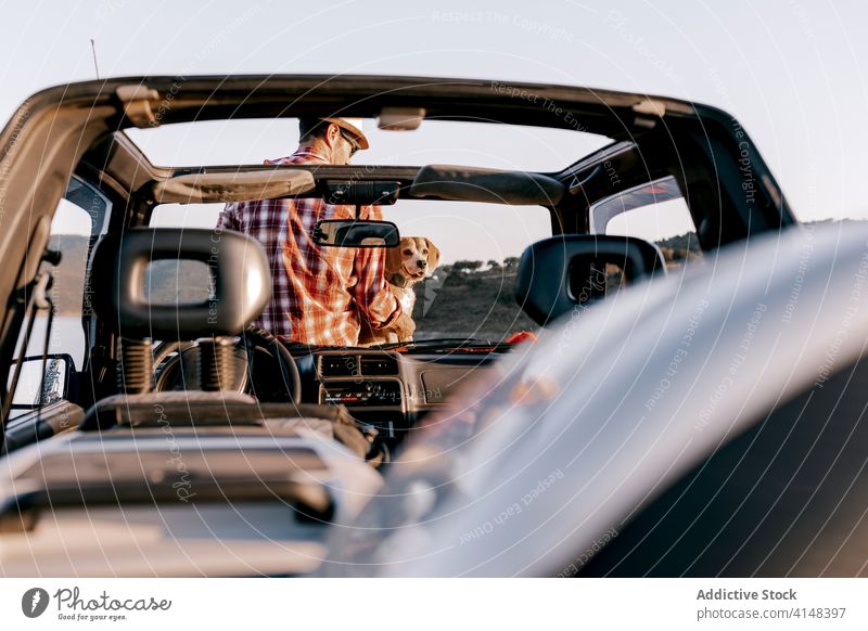 Anonymous tourist with Hovawart enjoying nature sitting on car in sunlight dog admire river mountain vacation beauty idyllic contemplate highland travel