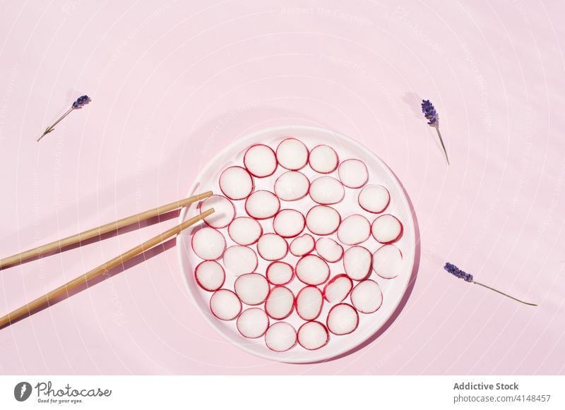 Cut radish and chopsticks on pink background vegetable fresh arrangement lavender flower ripe cut plate wooden healthy organic natural bloom plant blossom