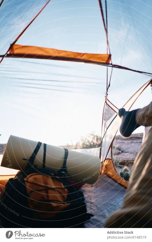 Anonymous traveler resting in tent hiker relax backpacker camp leg lying trekking nature sunny summer adventure journey vacation lifestyle tourism freedom