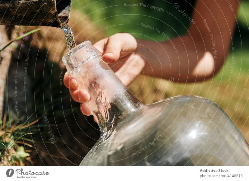 Woman with bottle of water in countryside natural spring woman aqua fill pour fresh refreshment female sunhat dress plastic nature beverage summer liquid