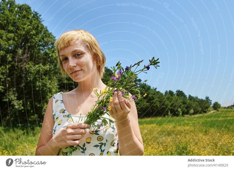 Smiling woman in blooming field summer bouquet meadow flower blossom sunny content dress female happy countryside young enjoy fresh smile relax floral lady