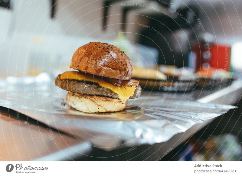 Fresh hamburger with patty and cheese fast food cutlet meal beef bun foil tradition serve cuisine appetizing fresh lunch tasty meat snack sesame delicious