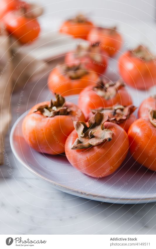 Ripe persimmons on plate in kitchen fruit sweet pile fresh vitamin diet nutrition nutrient delicious bright table healthy heap natural food healthy food organic