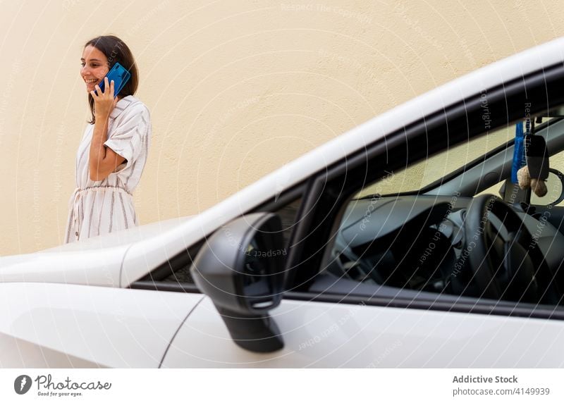 Smiling woman talking on smartphone near car speak driver parking lot modern using conversation female automobile transport vehicle device gadget smile