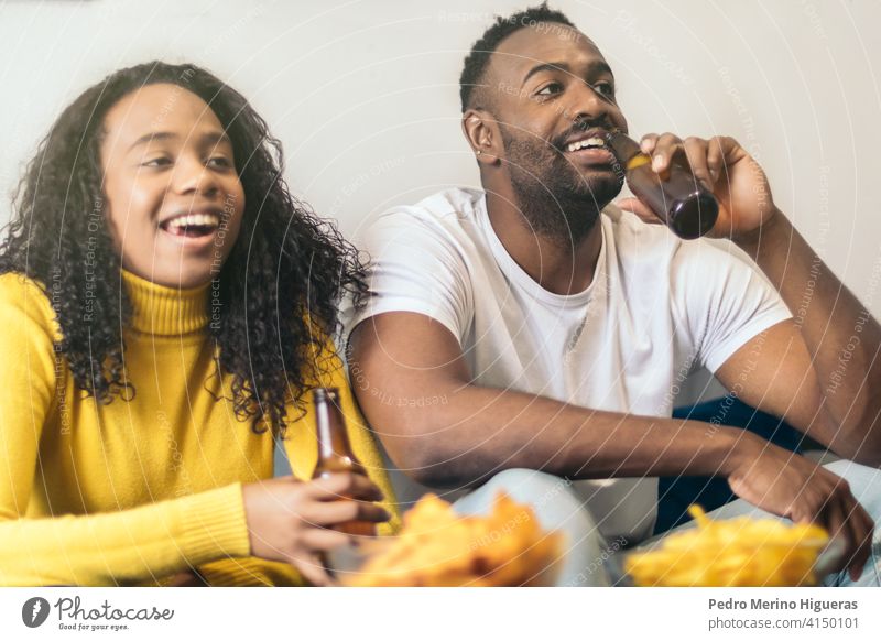 afro-american couple smiling and drinking beer at home happy african friends girlfriend boyfriend young together woman black alcohol fun leisure joy beverage