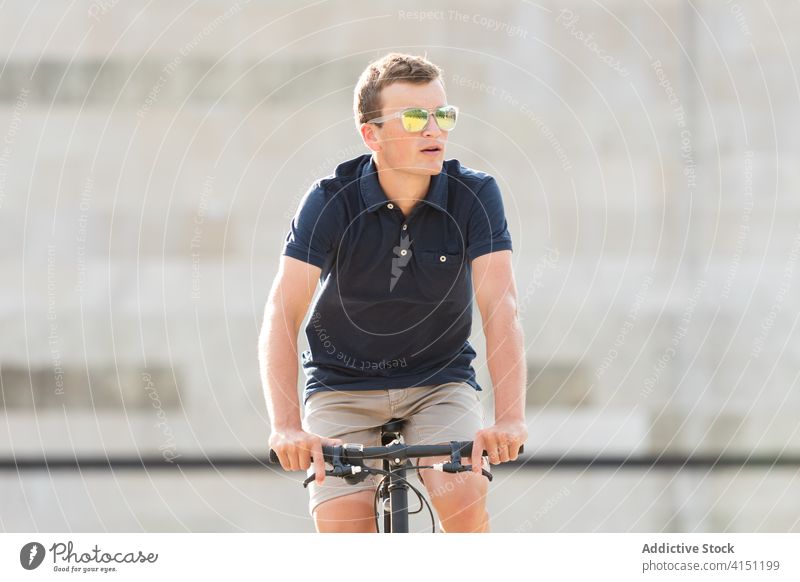 Young man riding bicycle on the street adult bike blond casual caucasian copy space ride cycling cyclist lifestyle male millennial mobility modern people