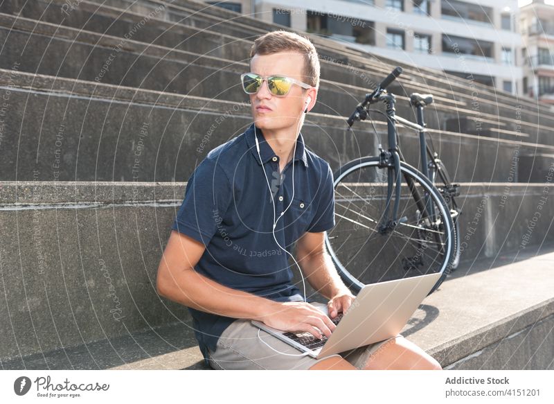 Man working on the street near his bicycle bike blond business caucasian communication computer copy space cycling cyclist entrepreneur freelance gadget