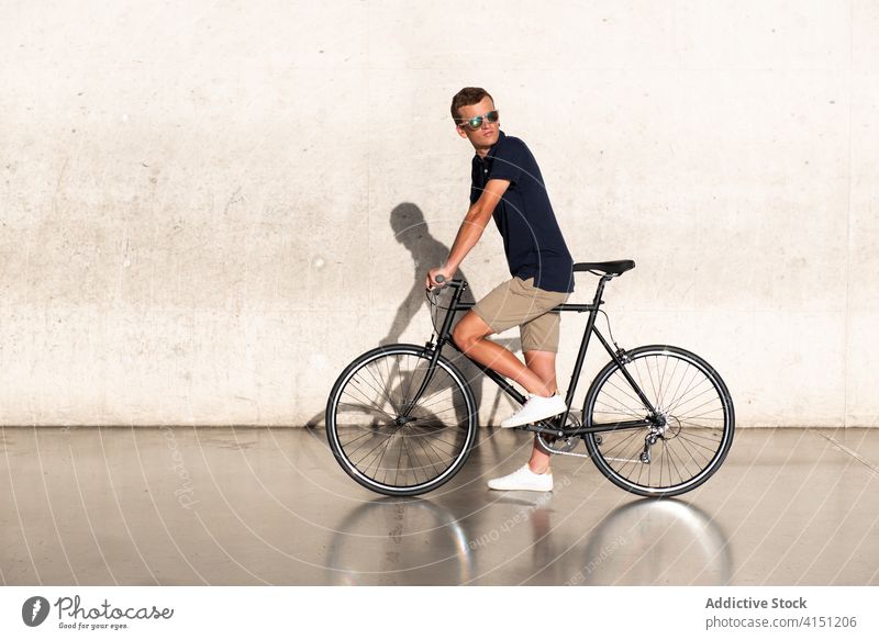 Man with bicycle on concrete wall adult bike blond casual caucasian copy space cycling cyclist lifestyle male man millennial mobility modern people serious