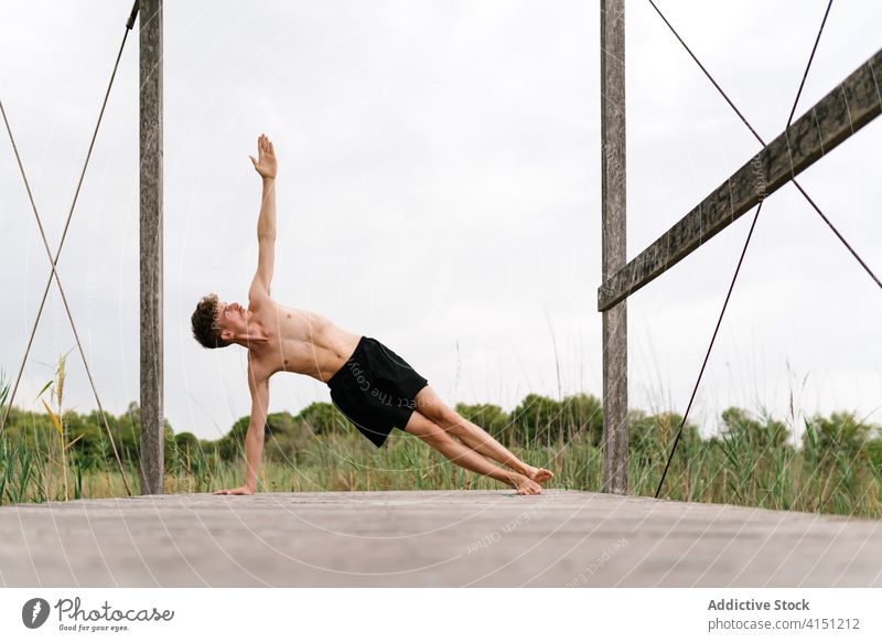 Flexible man doing yoga in Side Plank pose side plank practice flexible peaceful harmony nature terrace male healthy tranquil balance body vitality wellness