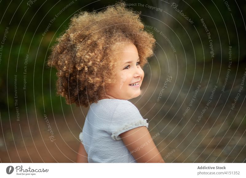 Happy curly haired girl in summer field happy cheerful kid smile portrait mixed race adorable hairstyle cute joy female ethnic afro child childhood charming