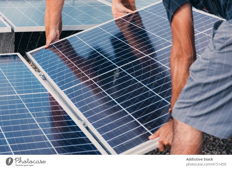 Anonymous male workers with solar panels in industrial area install battery men engineer together alternative sustainable development energy resource plant