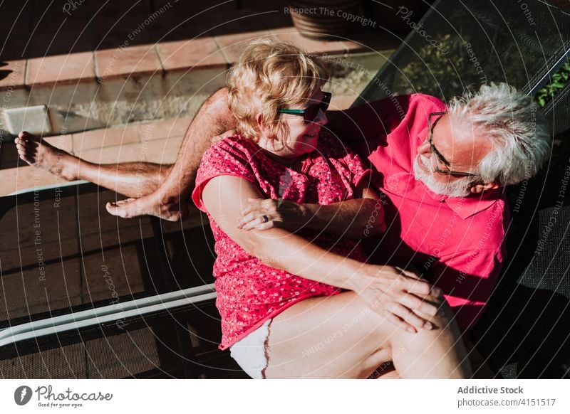 Loving senior couple relaxing on terrace elderly summer resort together lying deckchair sunbath hug vacation tender relationship holiday love happy travel sunny