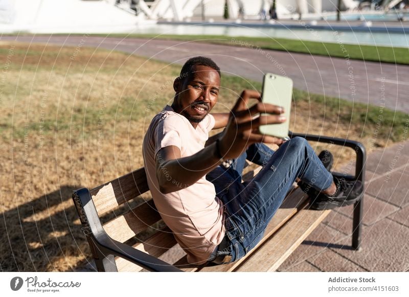 Black man taking selfie with phone park bench black people outdoor smartphone happy african american mobile cellphone smile happiness smiling technology picture