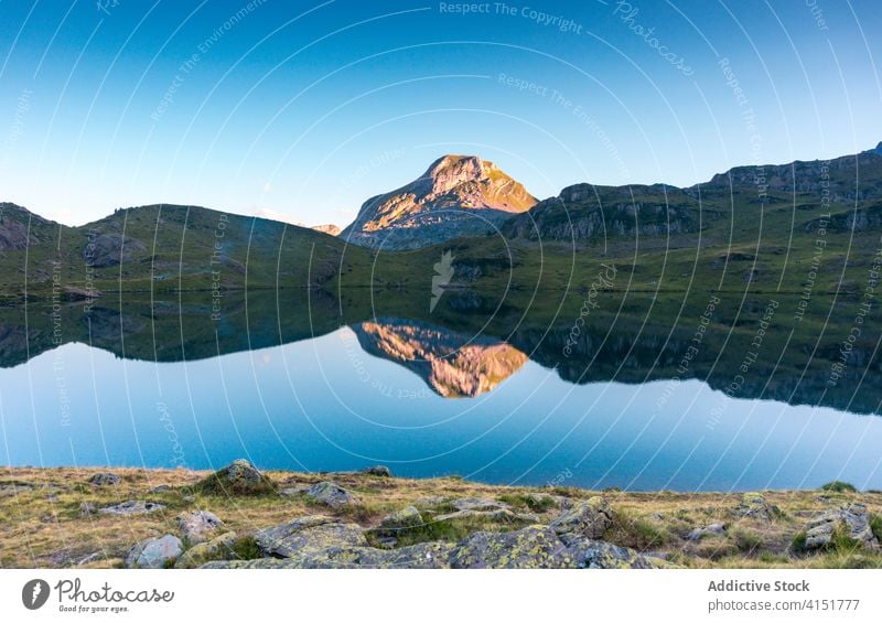 Rocky peak of mountain near lake top sunlight landscape rock majestic calm pond scenery scenic nature picturesque environment idyllic bright tranquil summer