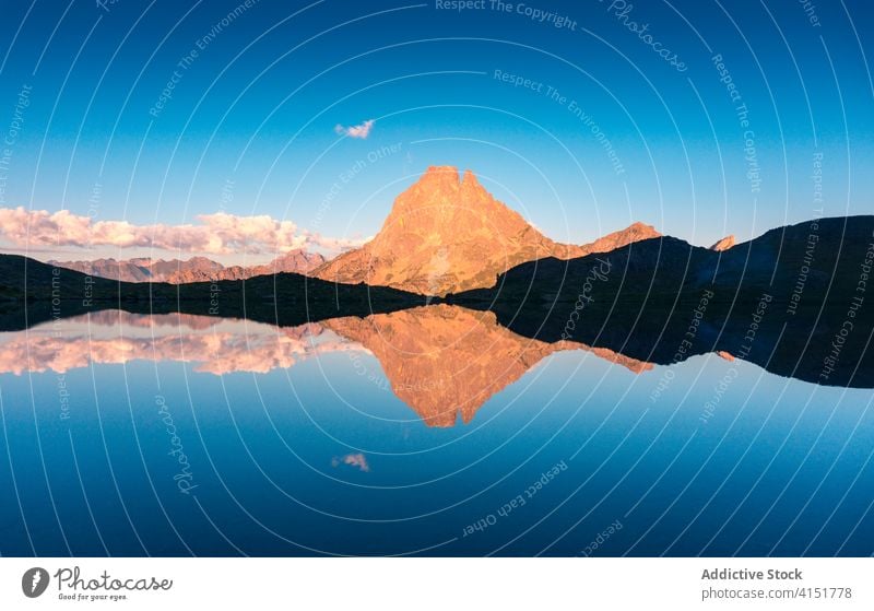 Rocky peak of mountain near lake top sunlight landscape rock majestic calm pond scenery scenic nature picturesque environment idyllic bright tranquil summer