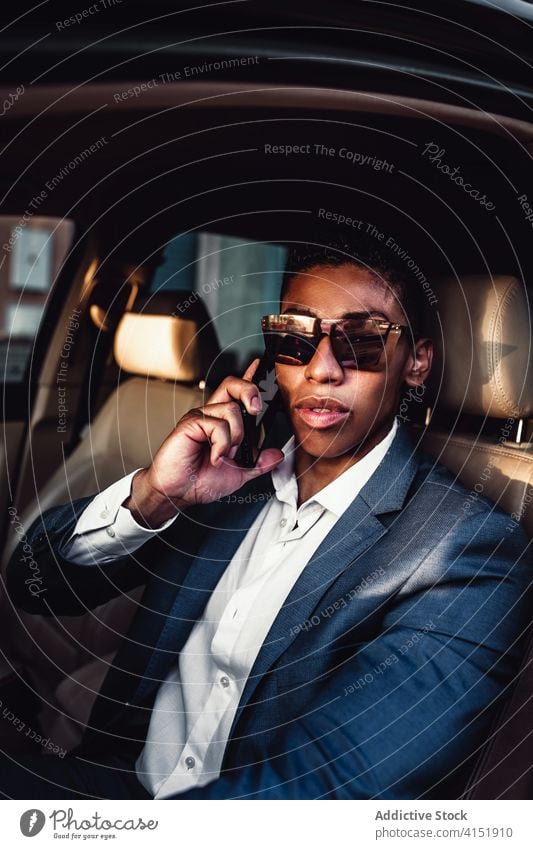 Smiling ethnic businessman talking on smartphone in car drive happy communicate positive urban formal young african american black male entrepreneur elegant