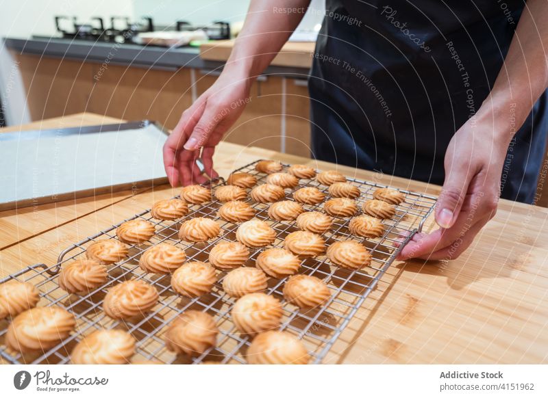 Faceless baker with ready cookies on rack bakery home hot cool kitchen person counter food pastry brown delicious small business team tasty cozy hands