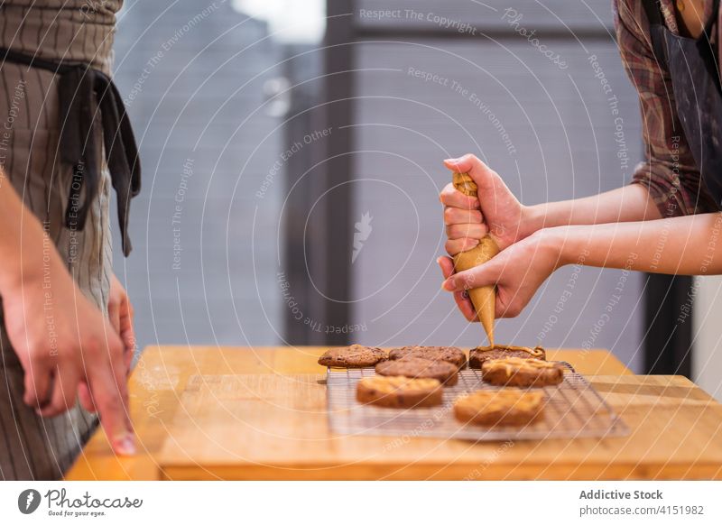 Anonymous bakers preparing cookies at home couple biscuit caramel pastry bag sauce topping chocolate chip together kitchen ethnic asian food culinary cuisine