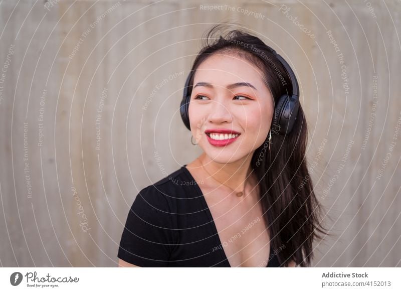 Carefree woman listening to music in headphones carefree smartphone using enjoy female ethnic asian happy cheerful sound modern gadget device young smile lady