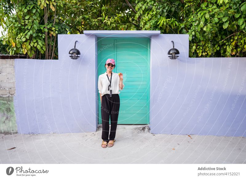 Cheerful ethnic female traveler looking at camera and waving hand woman summer tropical door entrance holiday cheerful wave hand friendly happy young asian